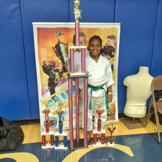  Krisdiana smiling while posing with six-foot trophy she took home from karate grand championship