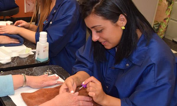 Cosmetology student paints a client's nails Cosmetology student paints a client's nails