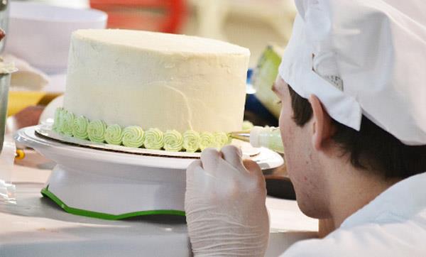 EMCC Culinary Arts student pipes decorative frosting onto a cake EMCC Culinary Arts student pipes decorative frosting onto a cake