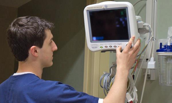 New Vision Medical Careers student checks hospital monitor New Vision Medical Careers student checks hospital monitor