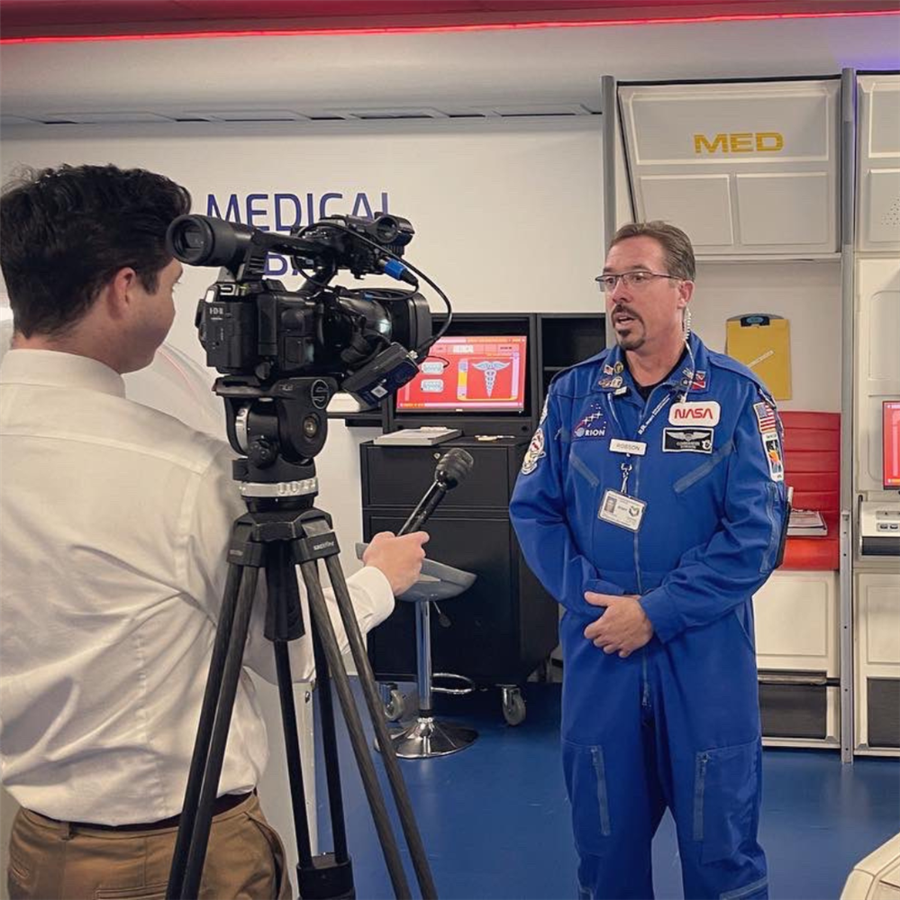  Commander Robson stands in front of a news camera while being interviewed at the challenger center